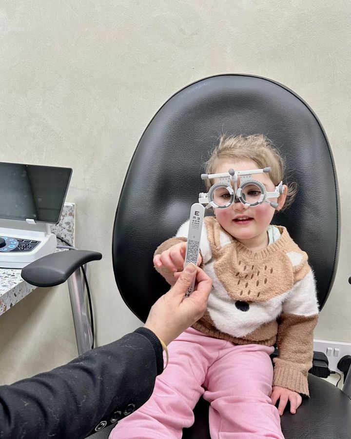 A young child reading an eye chart in trial frames